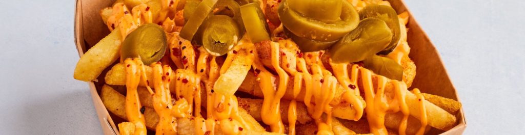 french fries with cheese sauce and jalapeno peppers on a tray being served at a restaurant