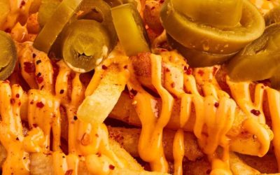 french fries with cheese sauce and jalapeno peppers on a tray being served at a restaurant