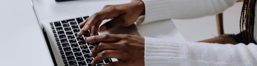 a young woman typing on an apple laptop