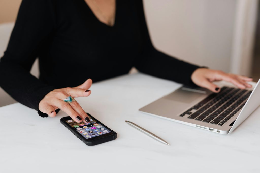 Woman using phone and laptop in office
