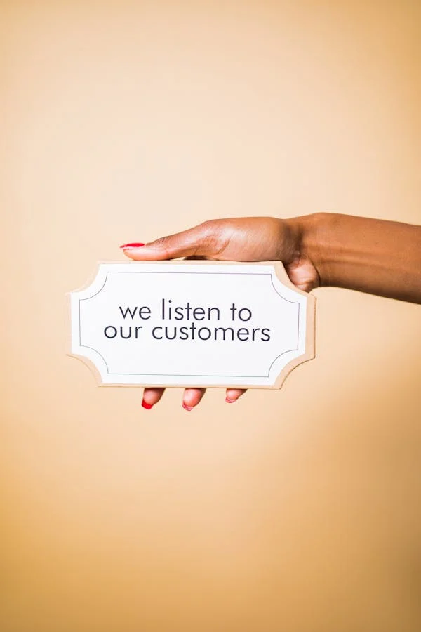 Hand holding a sign sayin we listen to our customers