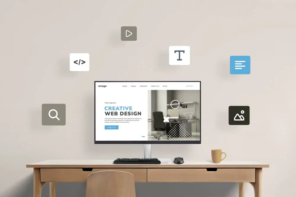 esktop computer on a minimalist desk displaying a creative web design interface with floating icons for coding, typography, and layout — Impact IQ Marketing Edmonton